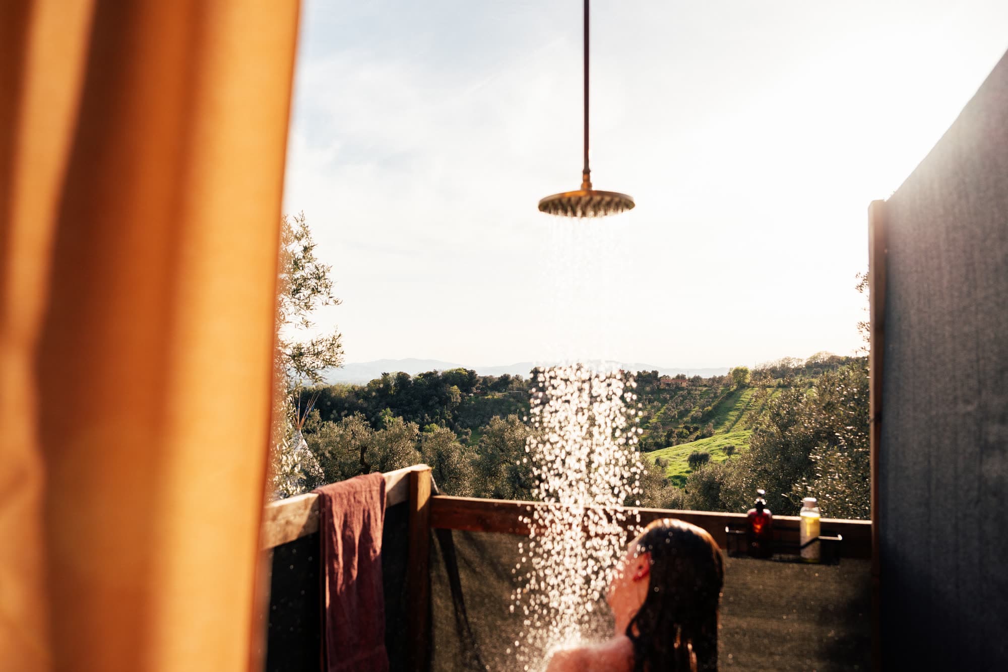 Regendusche im Gegenlicht, das Wasser fällt vor den Olivenhängen des Tals