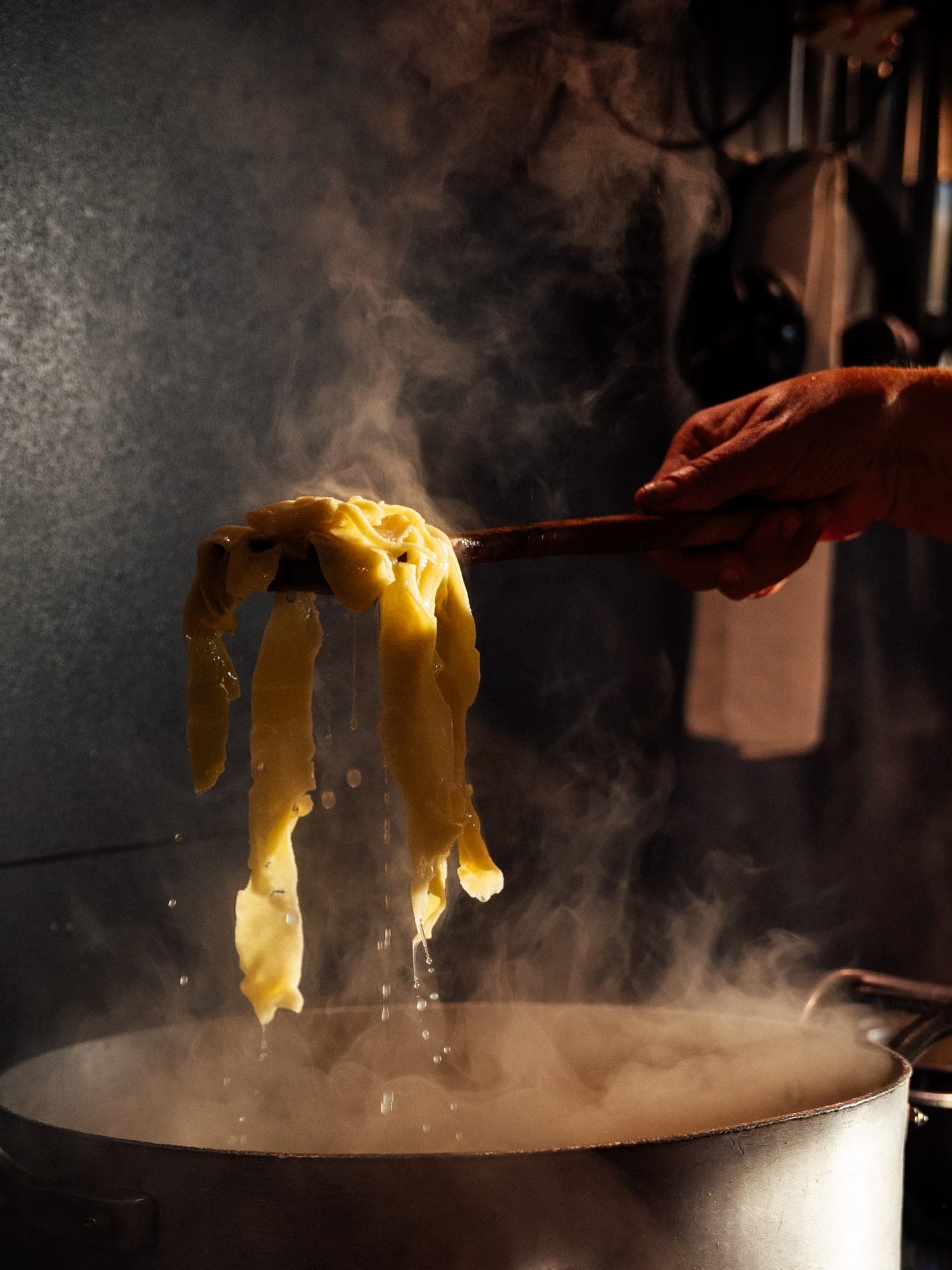 Frische Pappardelle werden dampfend mit einem Holzlöffel aus dem Kochtopf gehoben