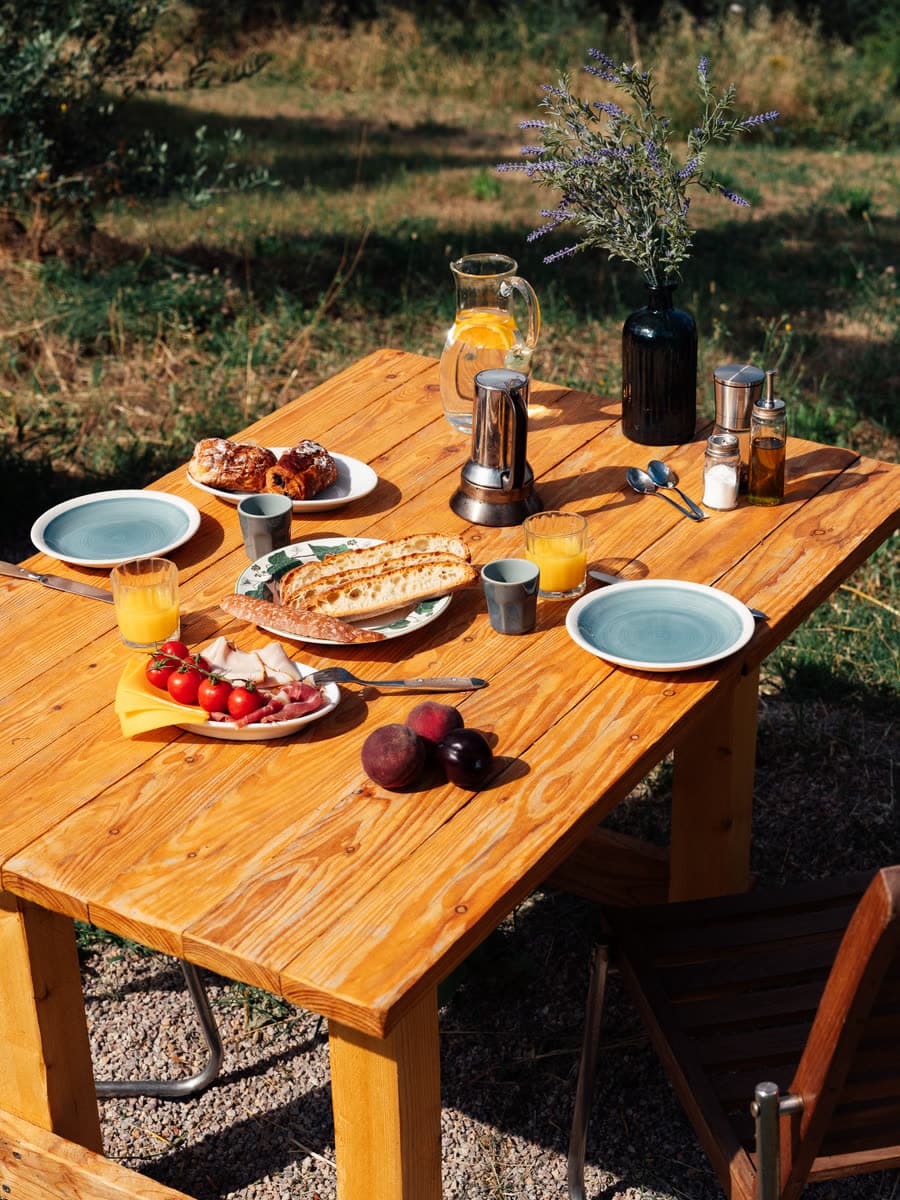 Morgenbord dækket udendørs med kaffekande, focaccia og appelsinjuice