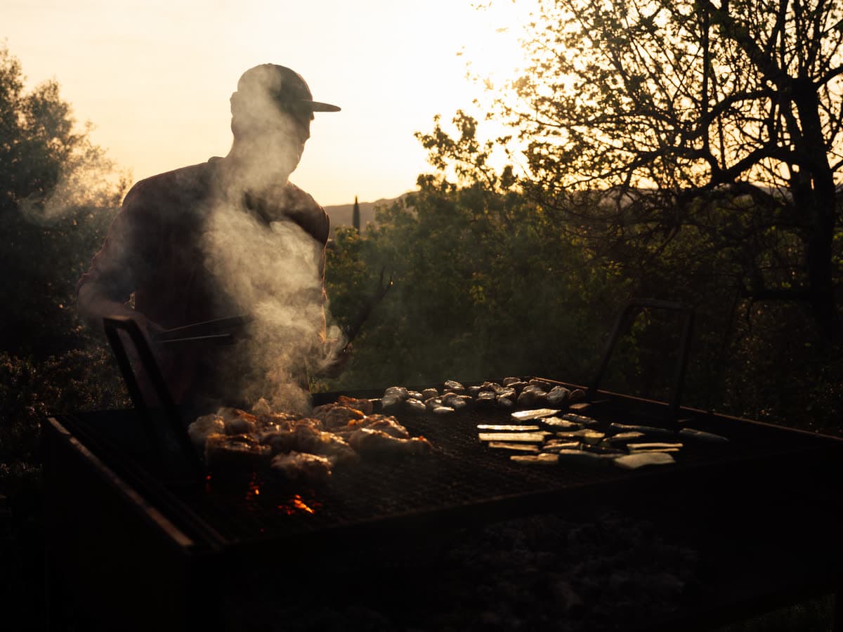 En person ved grillen i modlys, røgen står op foran dalen